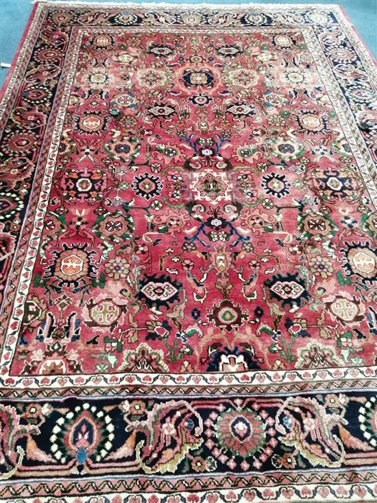 A Persian Nanaj red ground rug, all-over patterned with stylised floral motifs 300 x 215cm